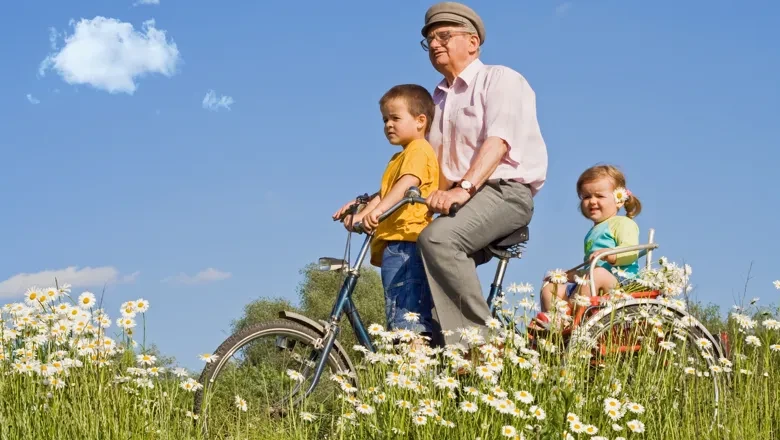 En äldre person och två barn på cykel